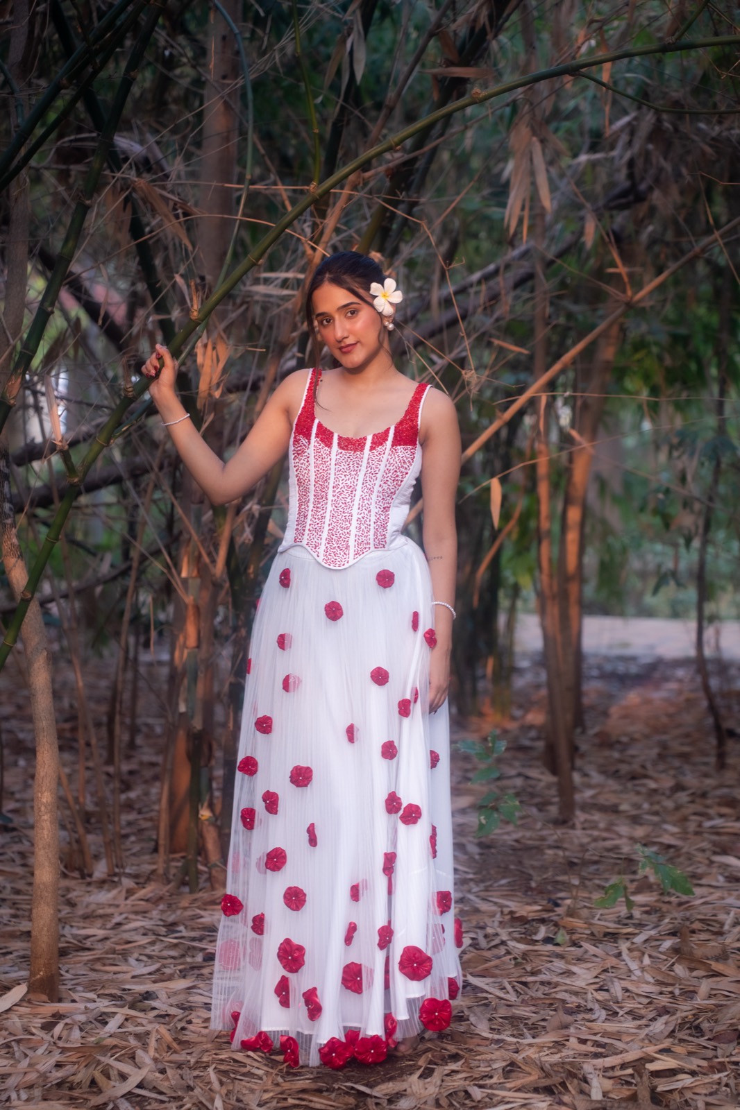 Carmine Rosette — white tulle gown with a red-beaded corset and carmine flowers, in a bamboo grove