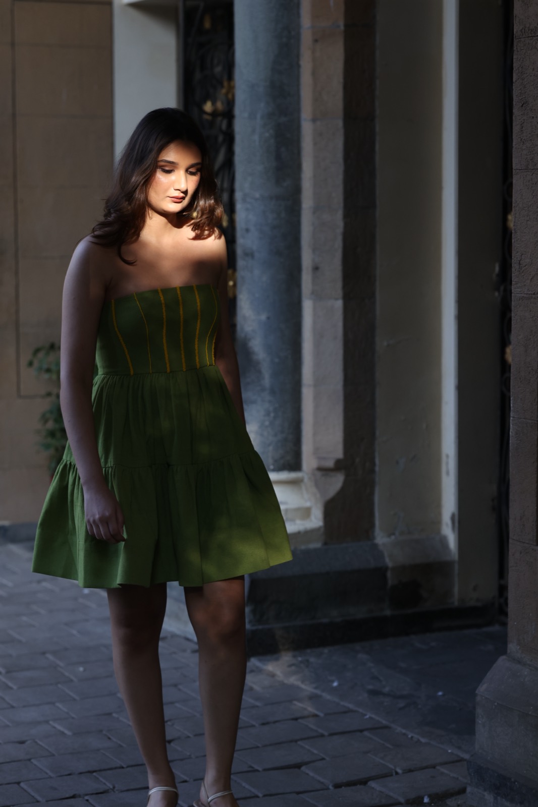 Green Tiered Mini — full length in the shade of the arcade, the contrast topstitching visible up the bodice