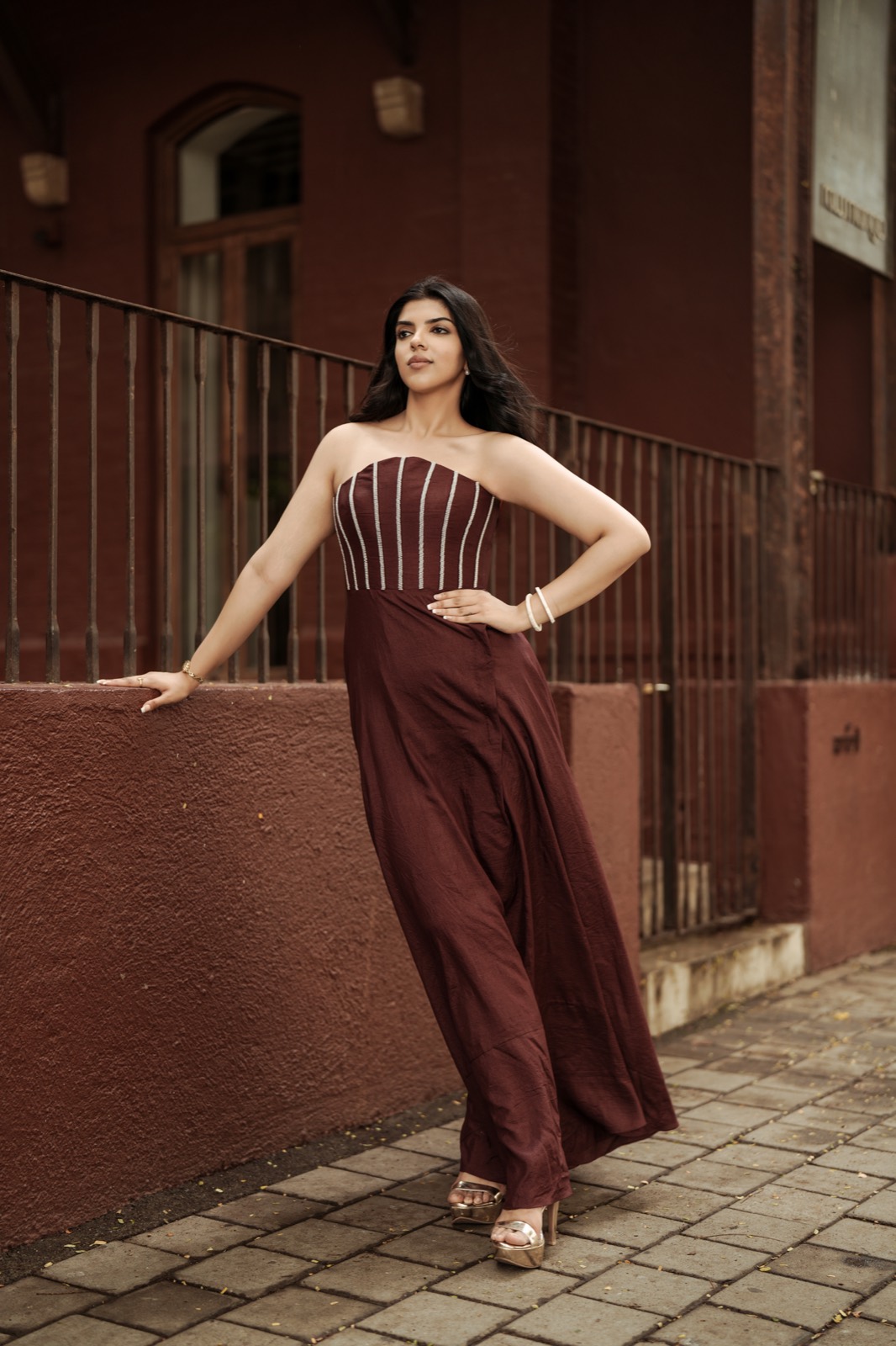 Pearl Syrup — an oxblood raw-silk gown, pearls down the corset bones, against a red-brown street wall