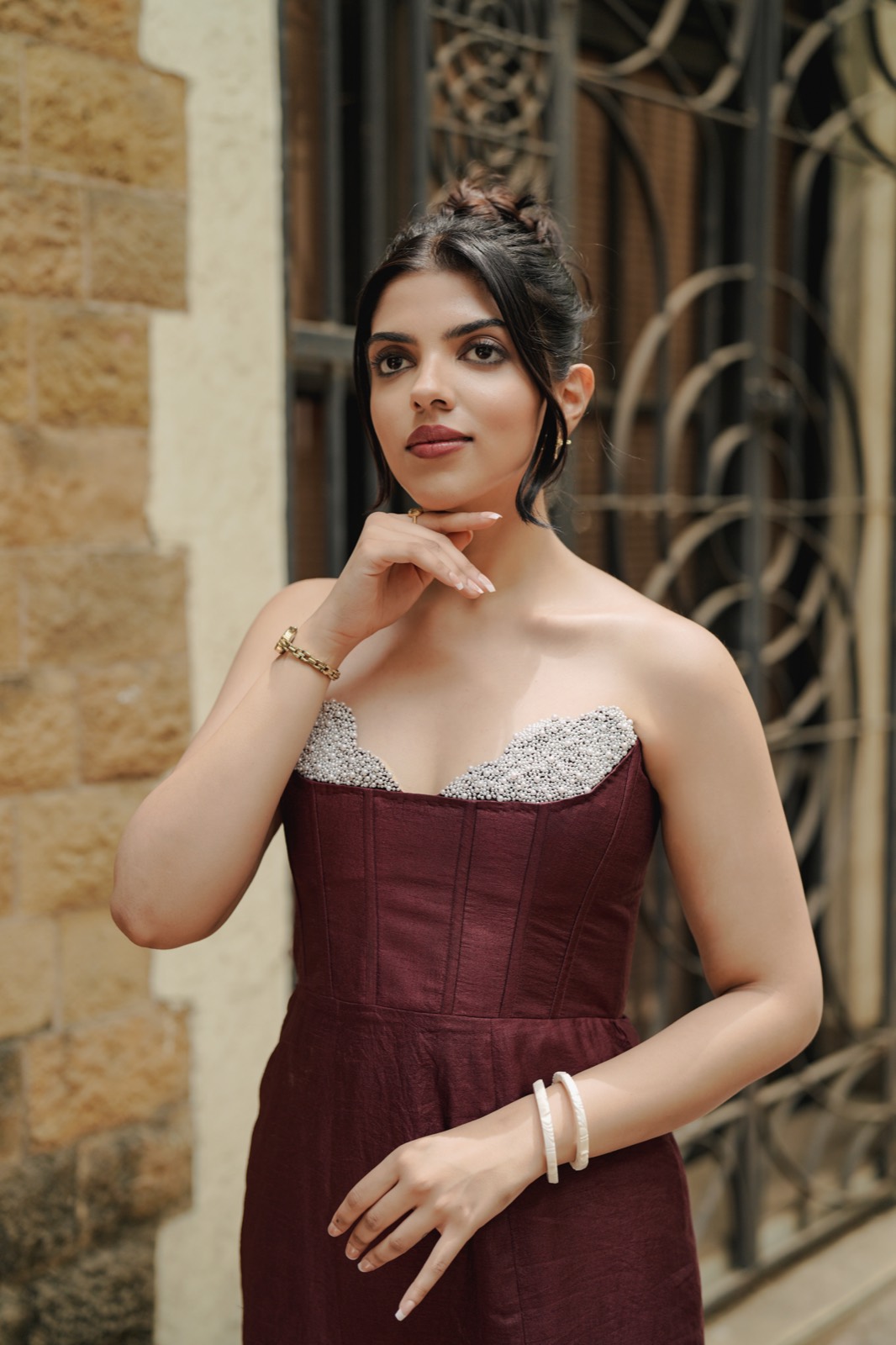 Claret Column — head and shoulders, the beaded sweetheart neckline against sandstone